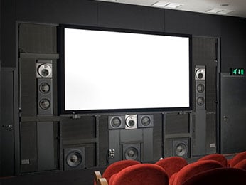 Prywatna sala kinowa w domu (pokój kinowy). Tuż pod ekranem znajduje się głośnik centralny - stały element kina domowego